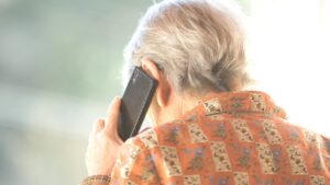 Senior woman on phone looking concerned, representing elder financial scam awareness.